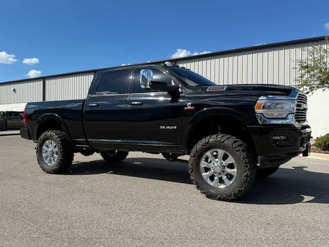 Black Ram pickup truck, lifted with large tires, parked outdoors on asphalt.