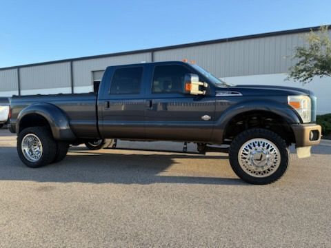 Dark gray Ford F 350 dually pickup truck with large chrome wheels parked outside a building.