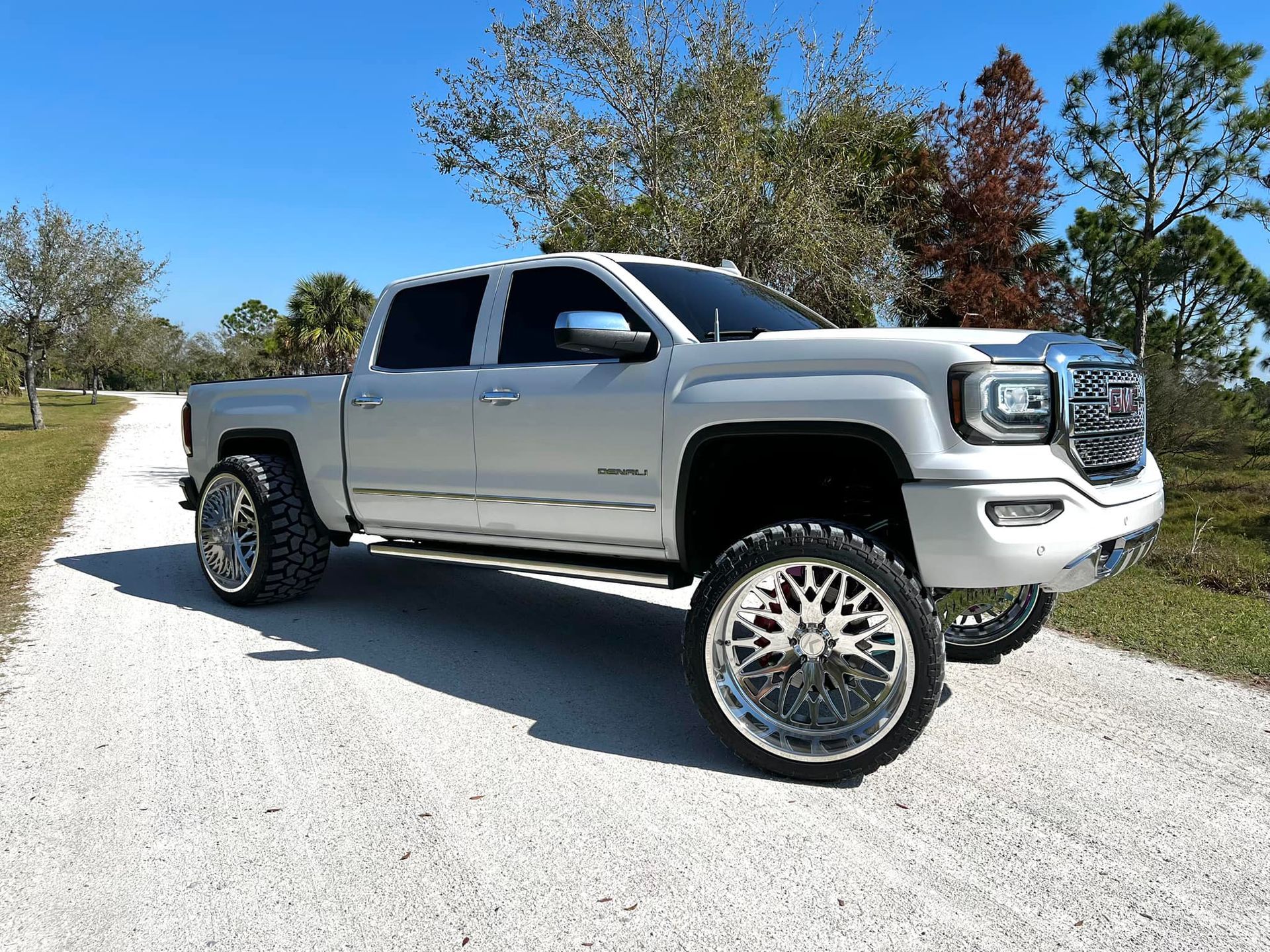 A silver truck is parked on the side of a dirt road.