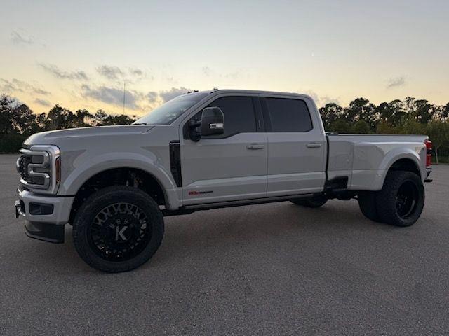 White dually truck with black wheels parked outdoors at dusk.