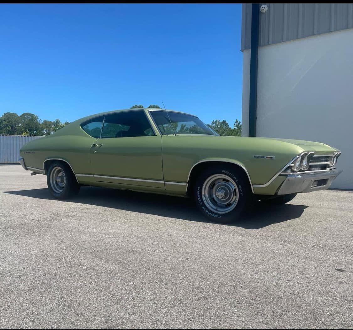 A green car is parked in front of a garage.
