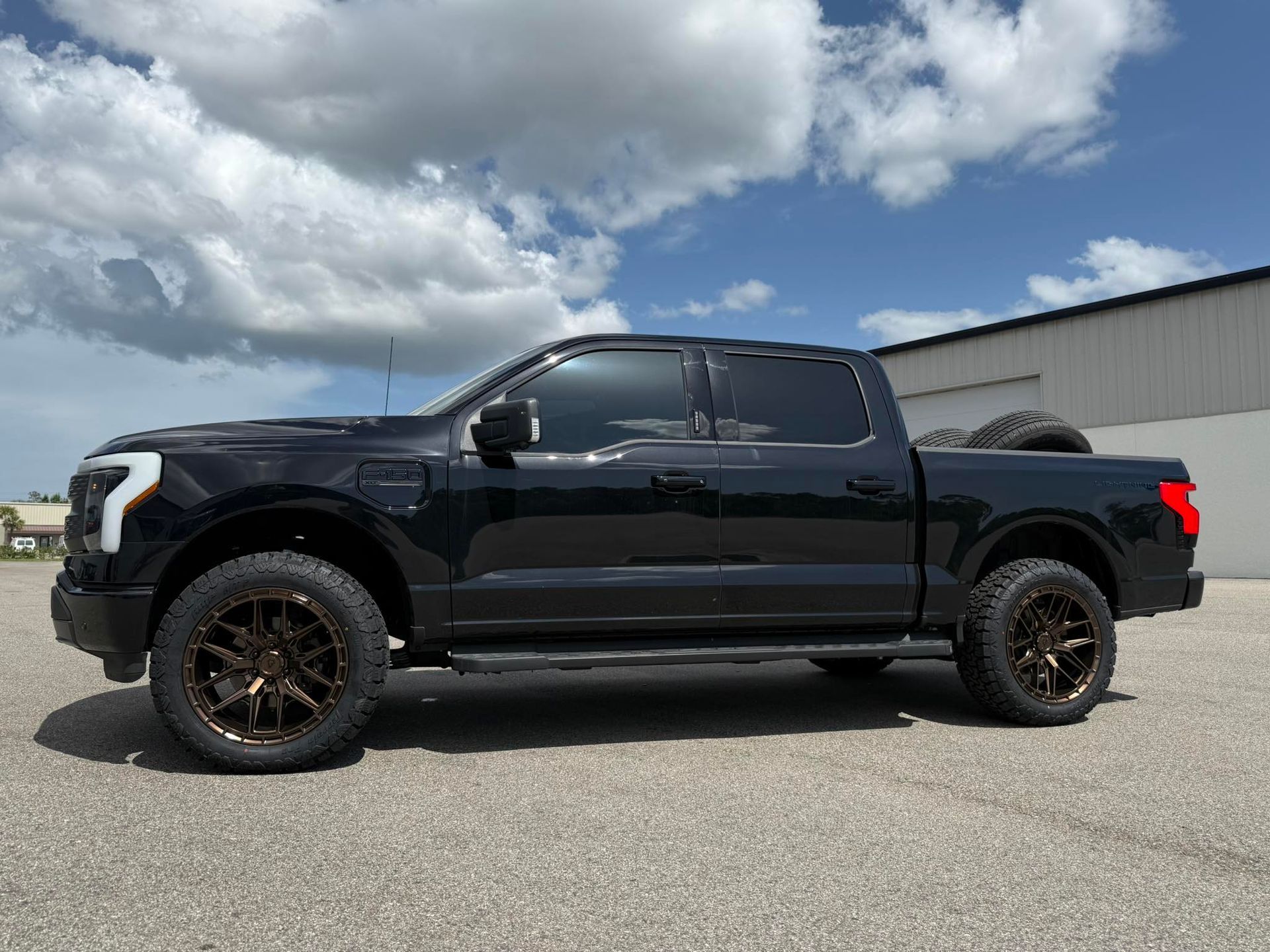 A black pickup truck is parked on the side of the road in front of a building.