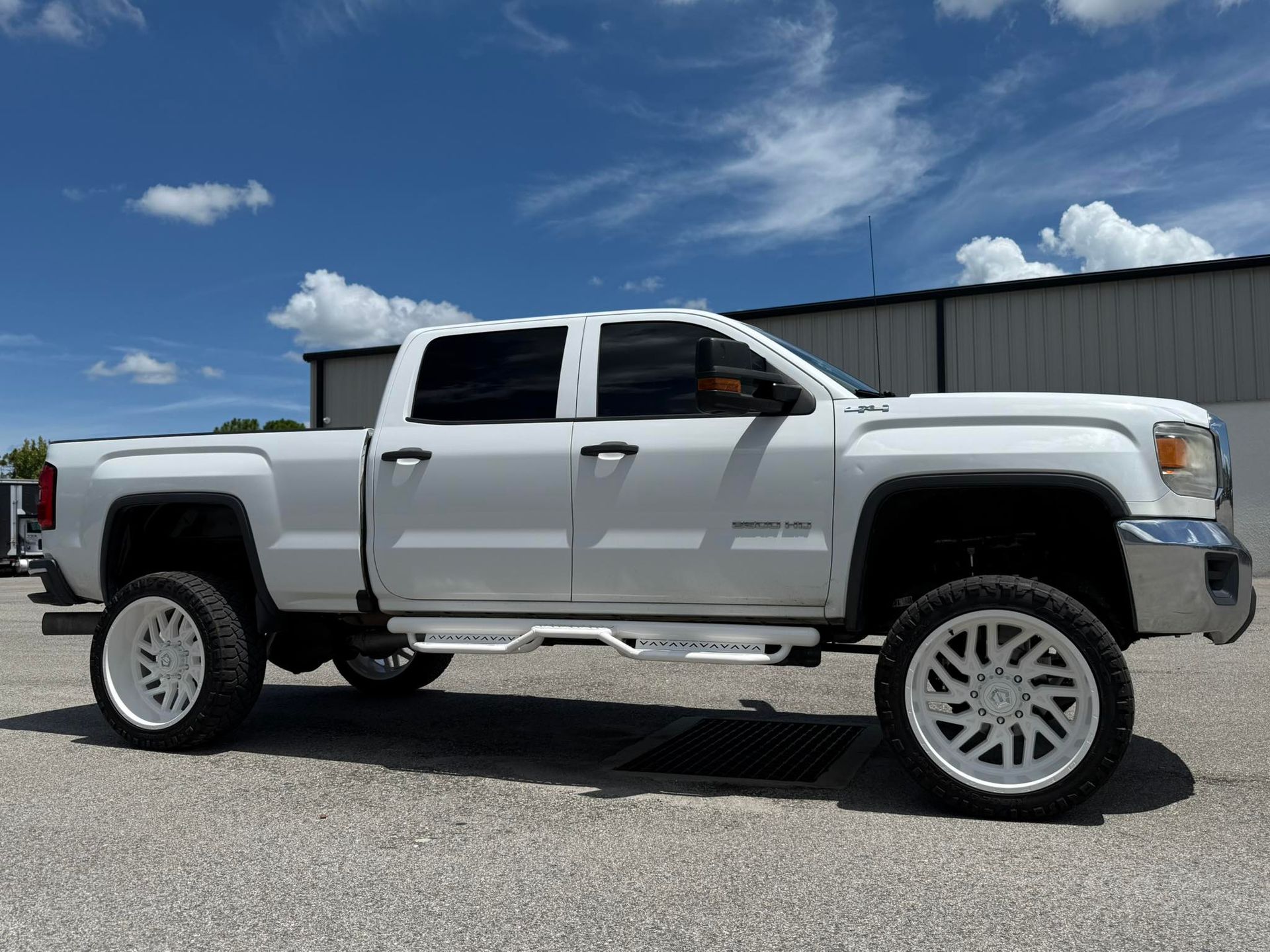 A white truck is parked in a parking lot in front of a building.