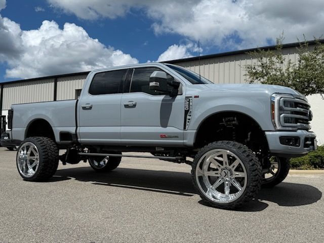 Gray lifted Ford truck with chrome wheels parked outdoors.