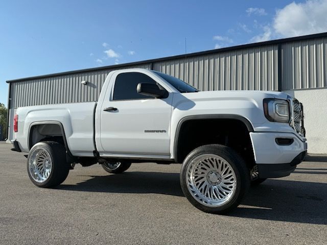 White GMC Sierra pickup truck with custom wheels parked in front of a building.