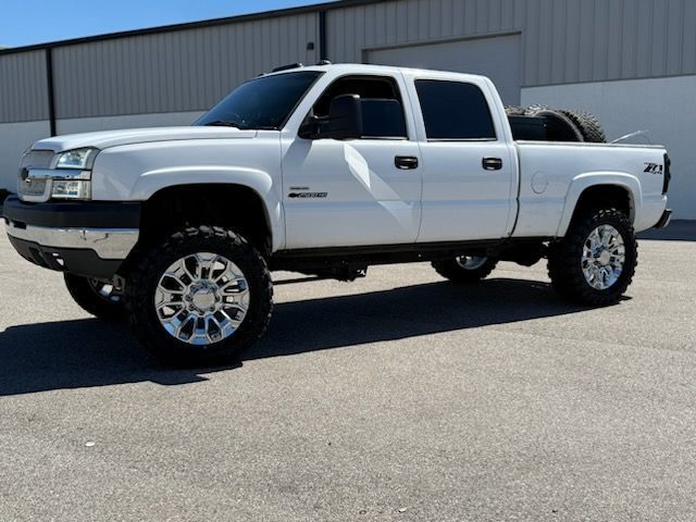 White Chevy pickup truck with large chrome wheels, parked on asphalt.