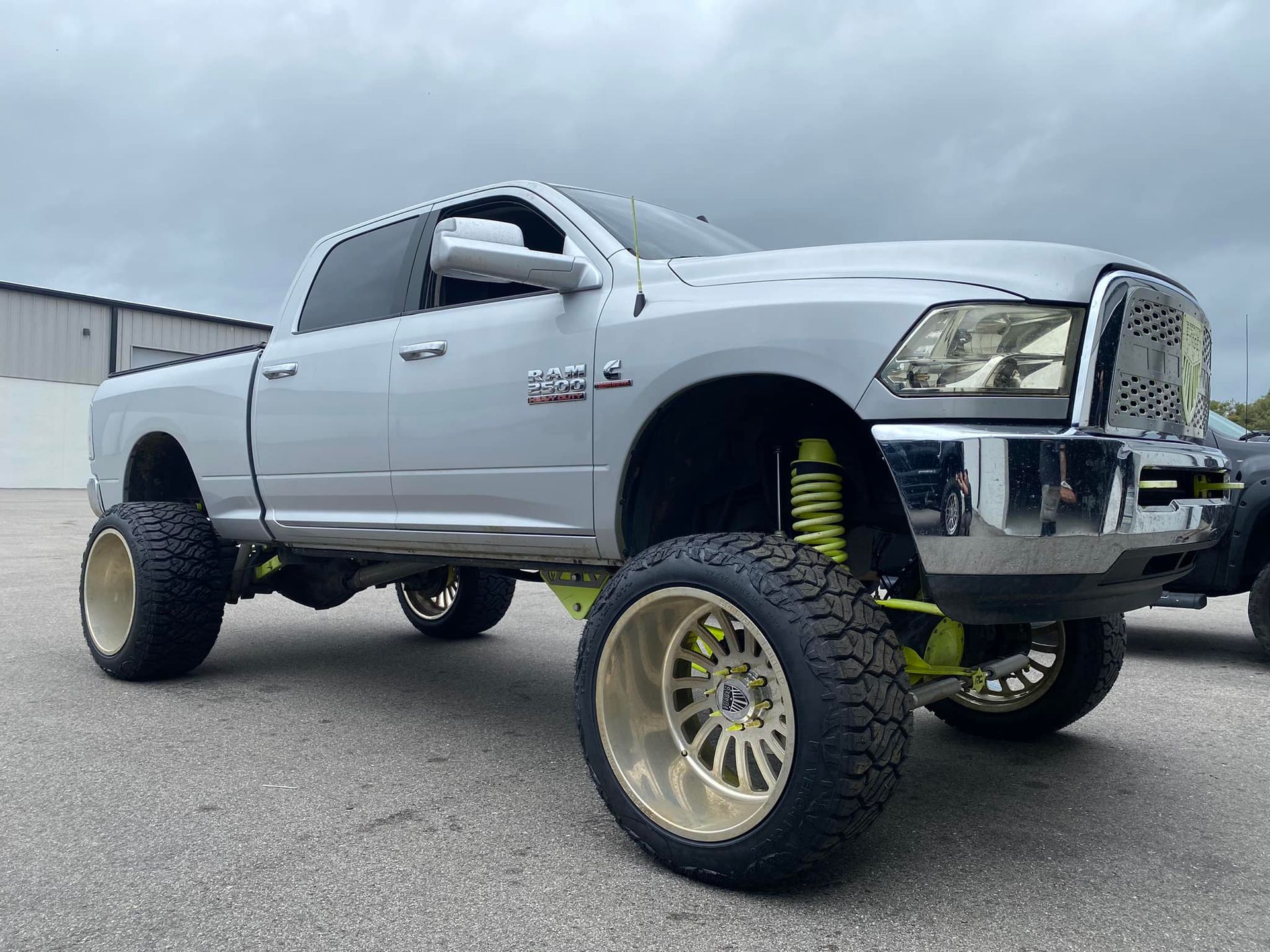 A silver dodge ram truck is parked on the side of the road.
