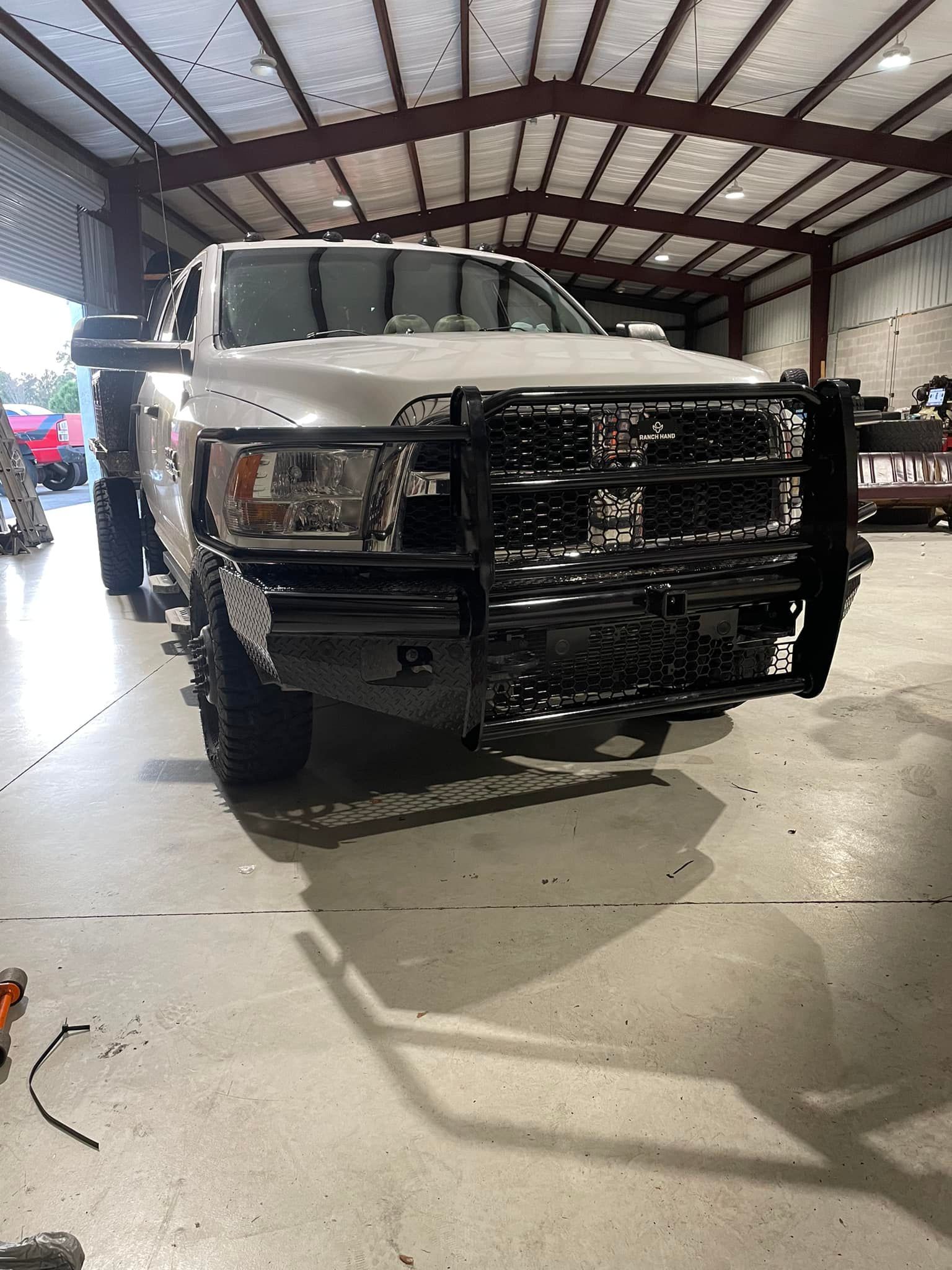 A white truck with a black bumper is parked in a garage.