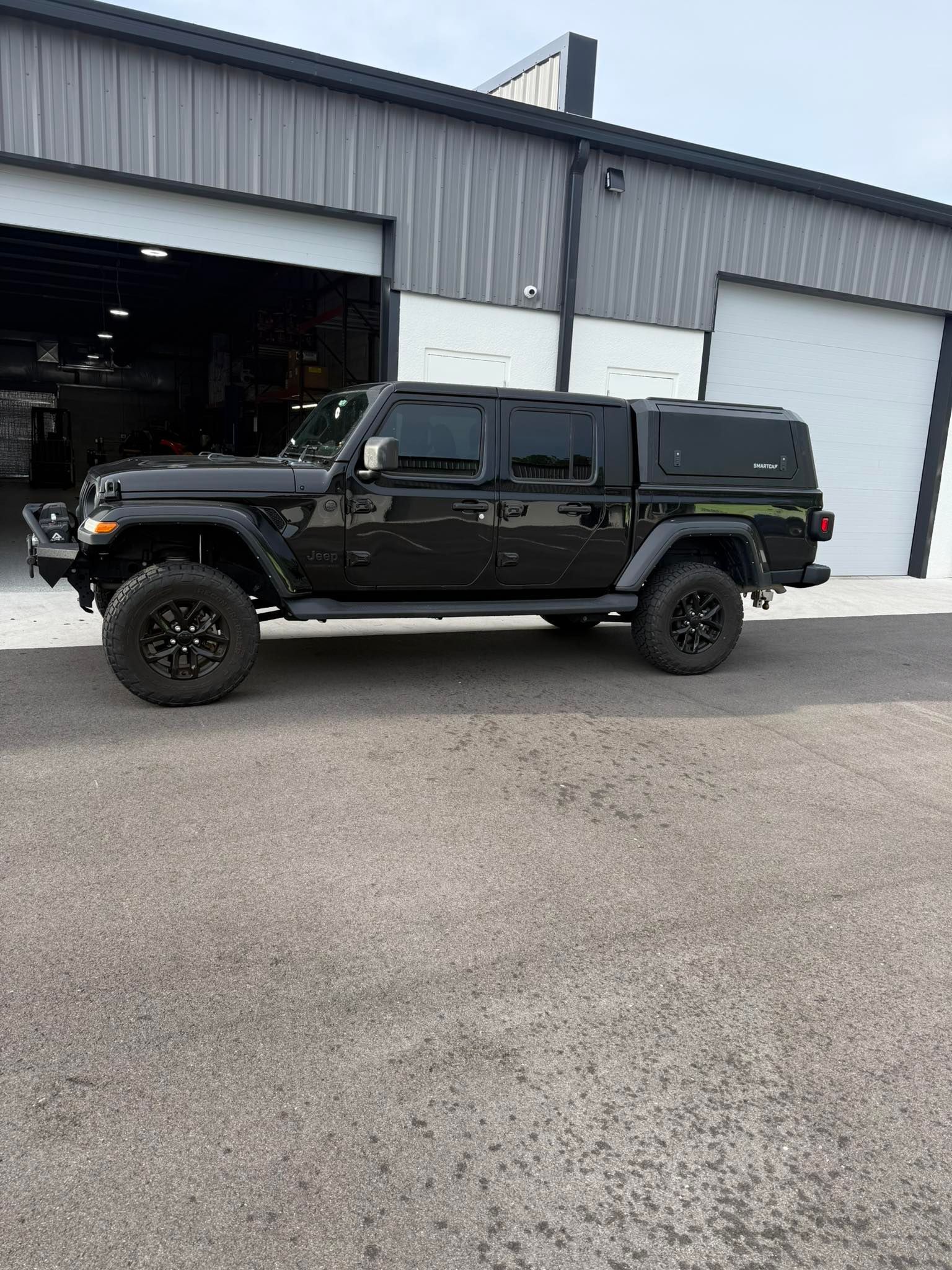 A black jeep is parked in front of a garage.
