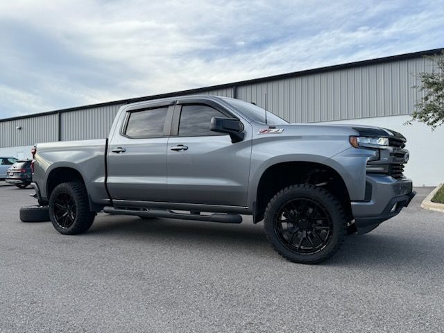 Gray Chevrolet Silverado truck with black wheels parked in front of a building.