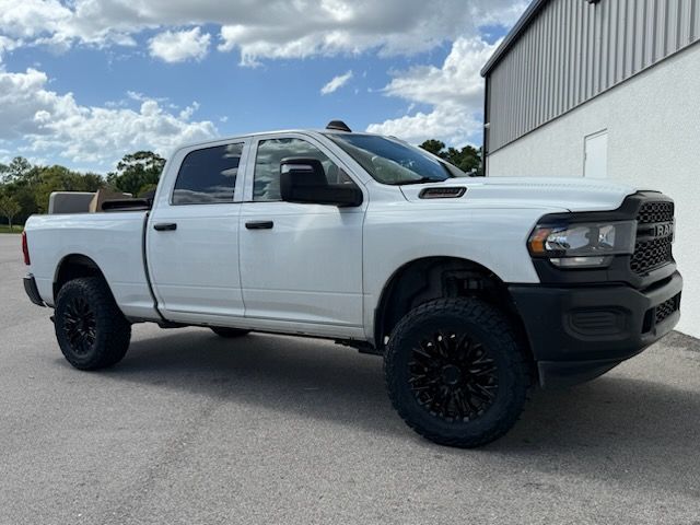 White Ram pickup truck parked on asphalt. Black wheels and brush guard. Bright sky.