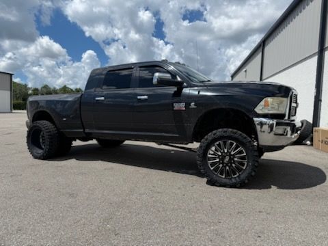 Black lifted Dodge Ram pickup truck with black and silver wheels parked outside.