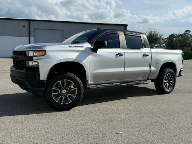 Silver Chevrolet Silverado pickup truck. Black accents, black wheels, and running boards. Parked outside.