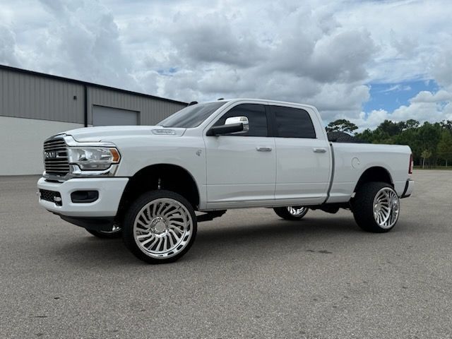 White Ram pickup truck with large chrome rims, parked outside a building.