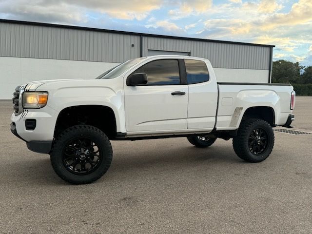 White pickup truck with black wheels parked in front of a building.