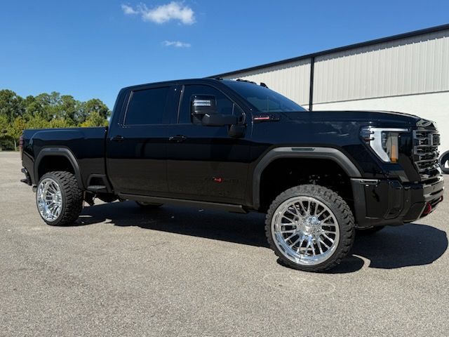 Black GMC truck with chrome wheels parked outdoors on a sunny day.