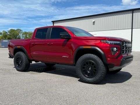 Red Chevrolet pickup truck parked in front of a building on a sunny day.