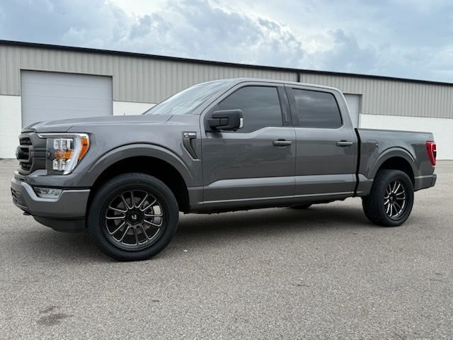 Gray Ford F 150 pickup truck with aftermarket wheels parked outdoors.
