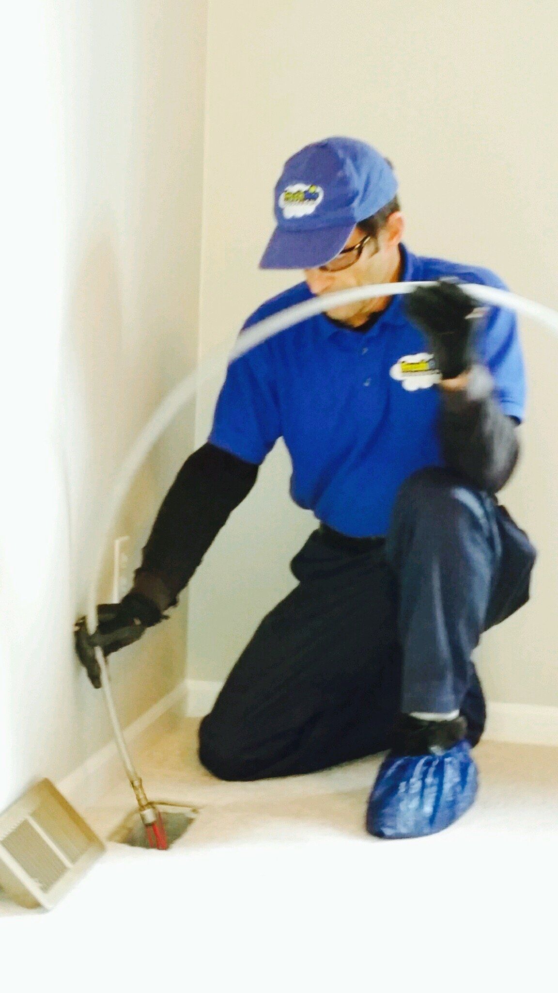 A man in a blue shirt and hat is kneeling down