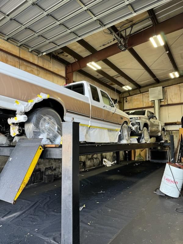 A truck is sitting on a lift in a garage.
