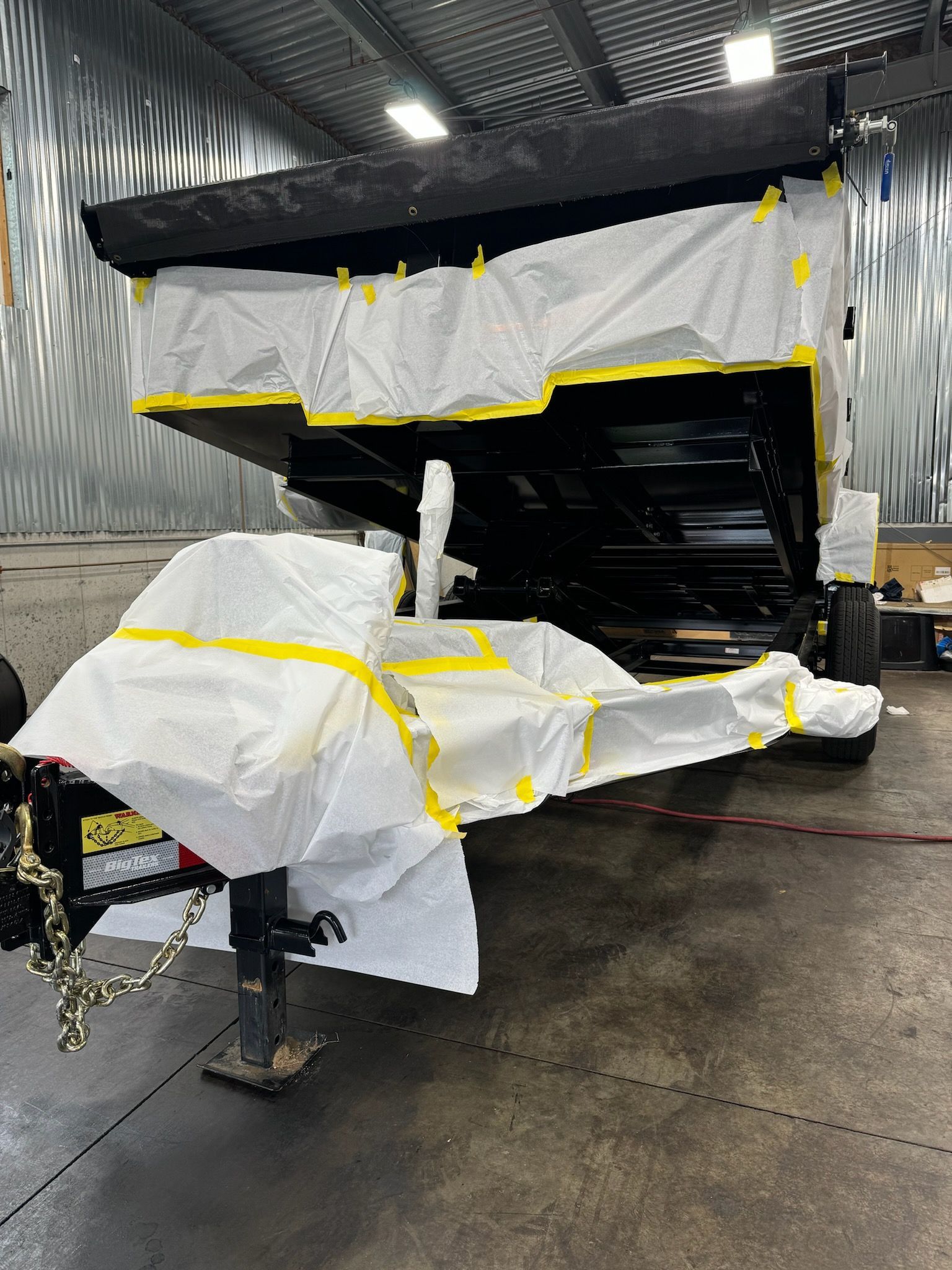 A trailer is being painted in a garage.