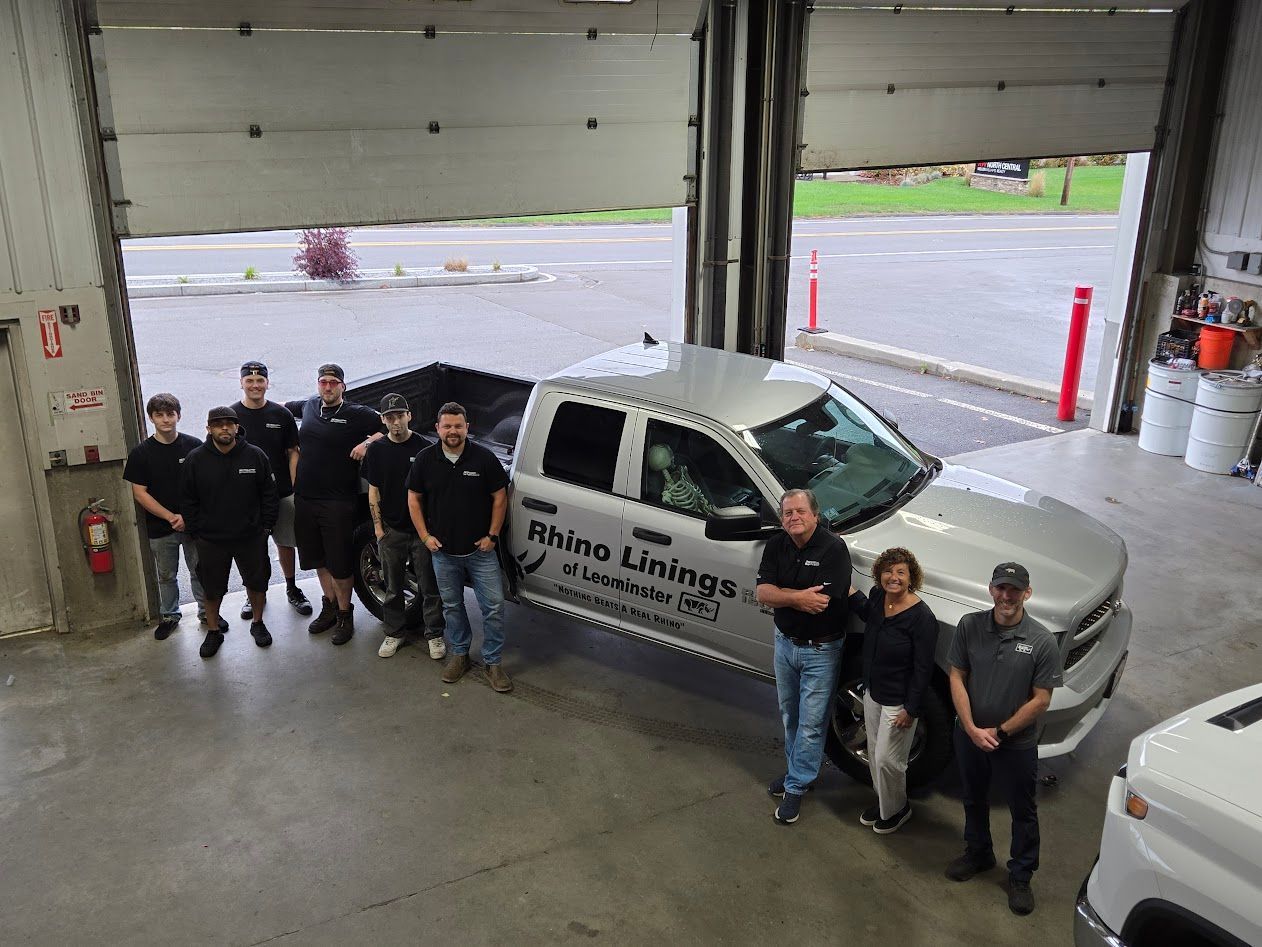 Group of people posing with silver truck in a garage.