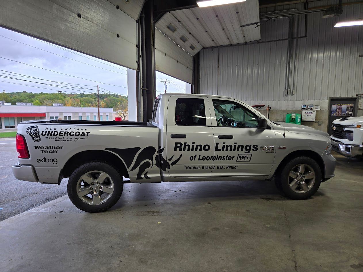 Silver pickup truck with Rhino Linings branding parked inside a garage.