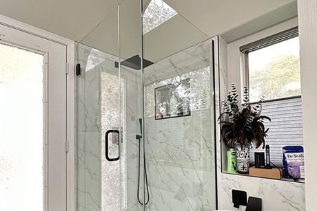 A bathroom with a walk in shower and a window.