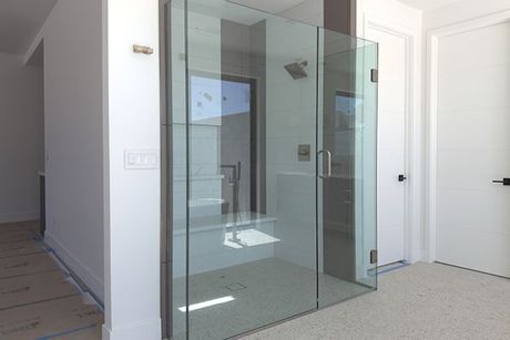 A bathroom with a walk in shower and a glass door.