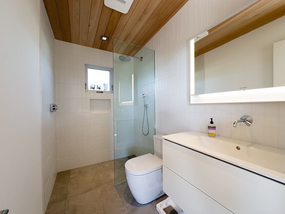 A bathroom with a toilet, sink, and walk in shower.