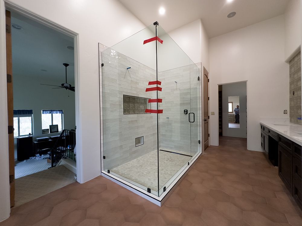 A bathroom with a walk in shower with a glass door