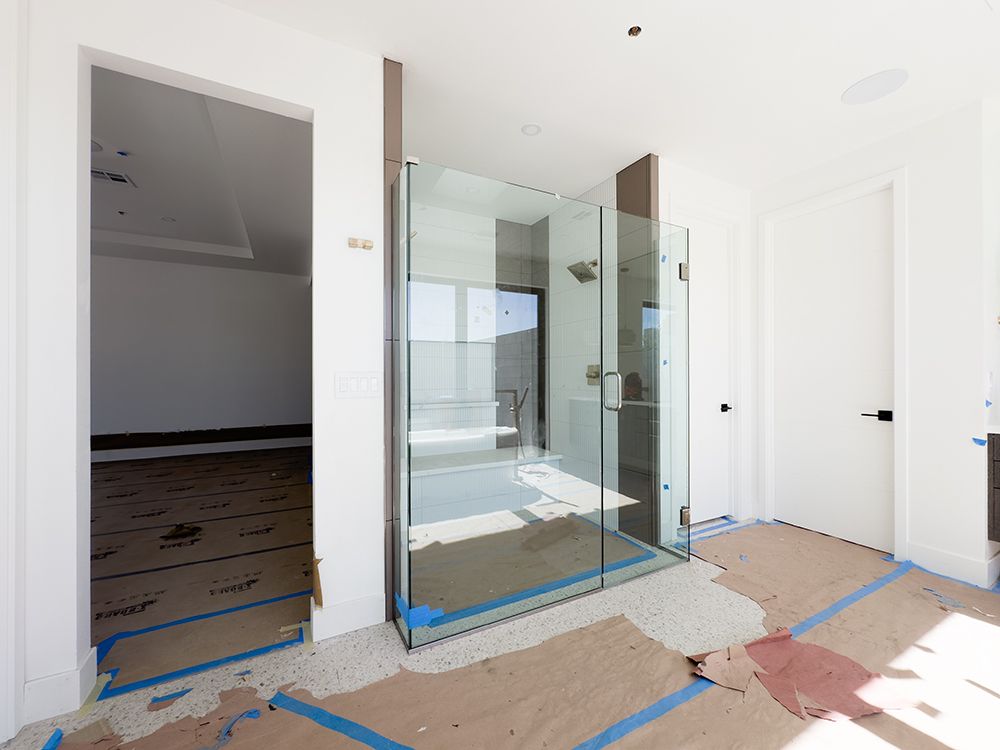 A bathroom in a house under construction with a glass shower door.