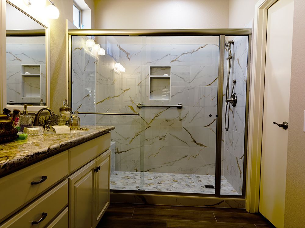 A bathroom with a walk in shower, sink and mirror.