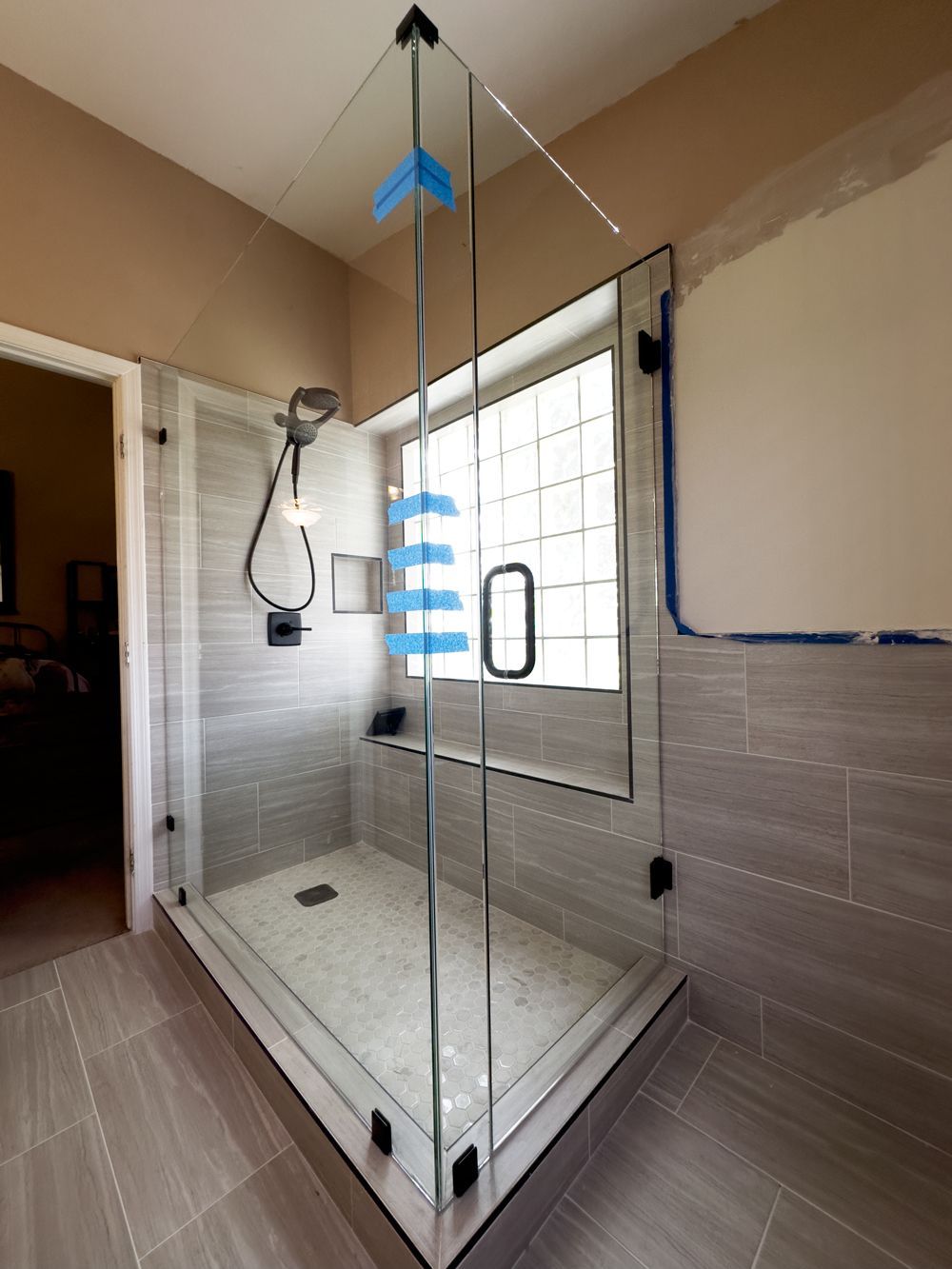A bathroom with a walk in shower and a window.