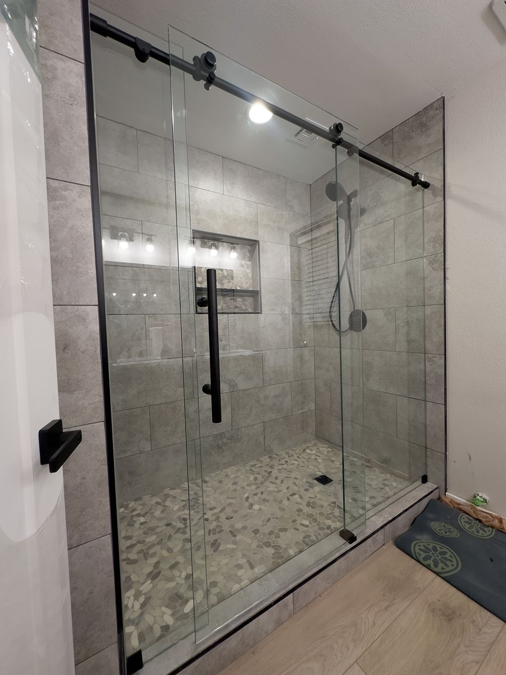 A bathroom with a sliding glass shower door and a shower head.