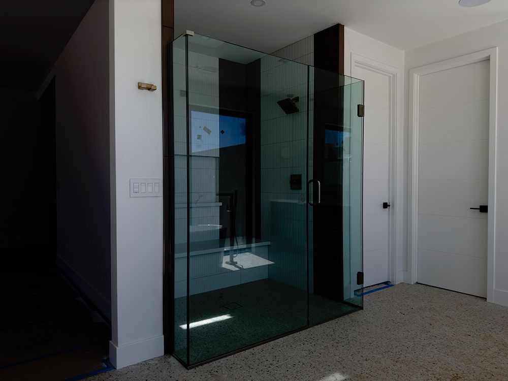 A bathroom with a walk in shower and a glass door.