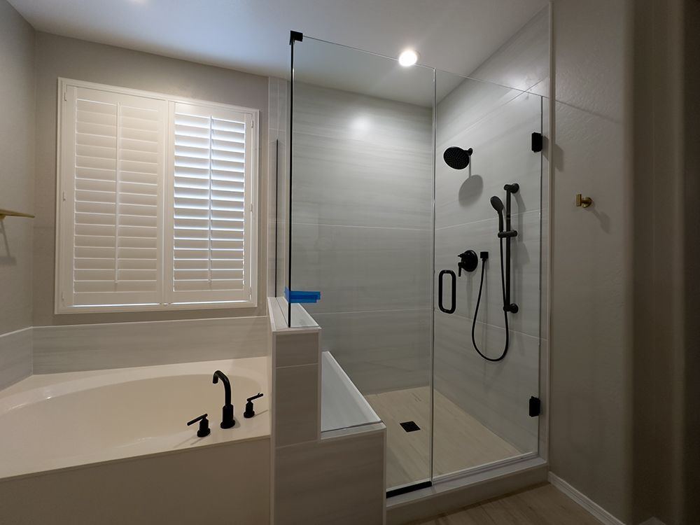 A bathroom with a tub and a walk in shower with a glass door.