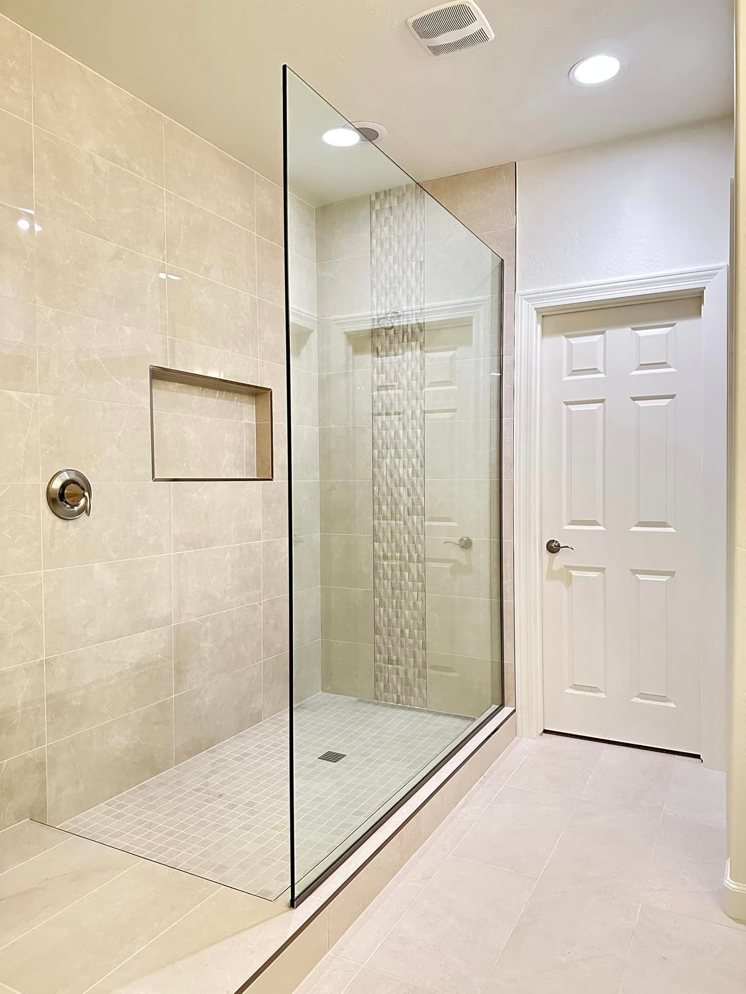 A bathroom with a walk in shower with a glass door.
