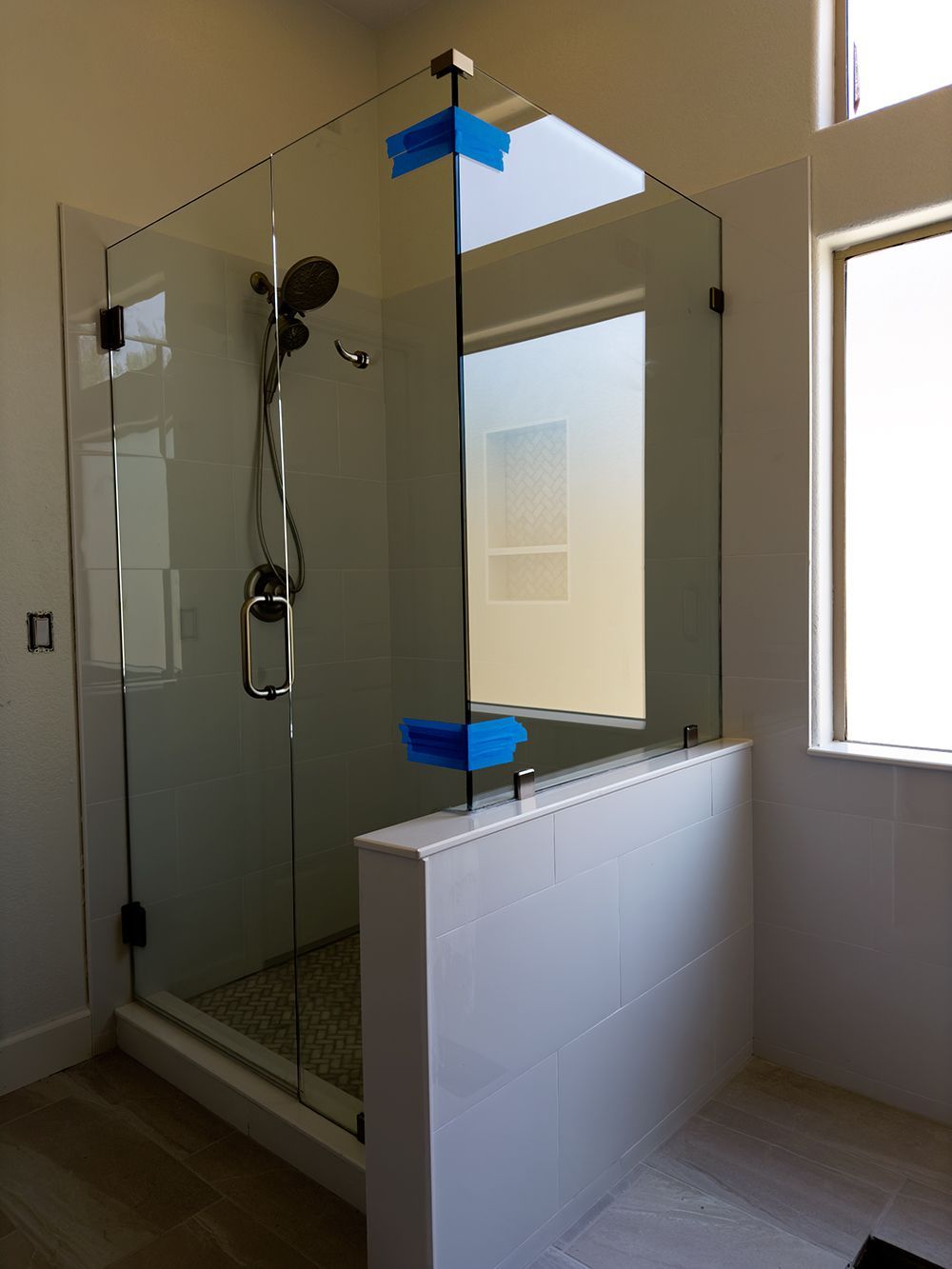A bathroom with a glass shower door and a window.