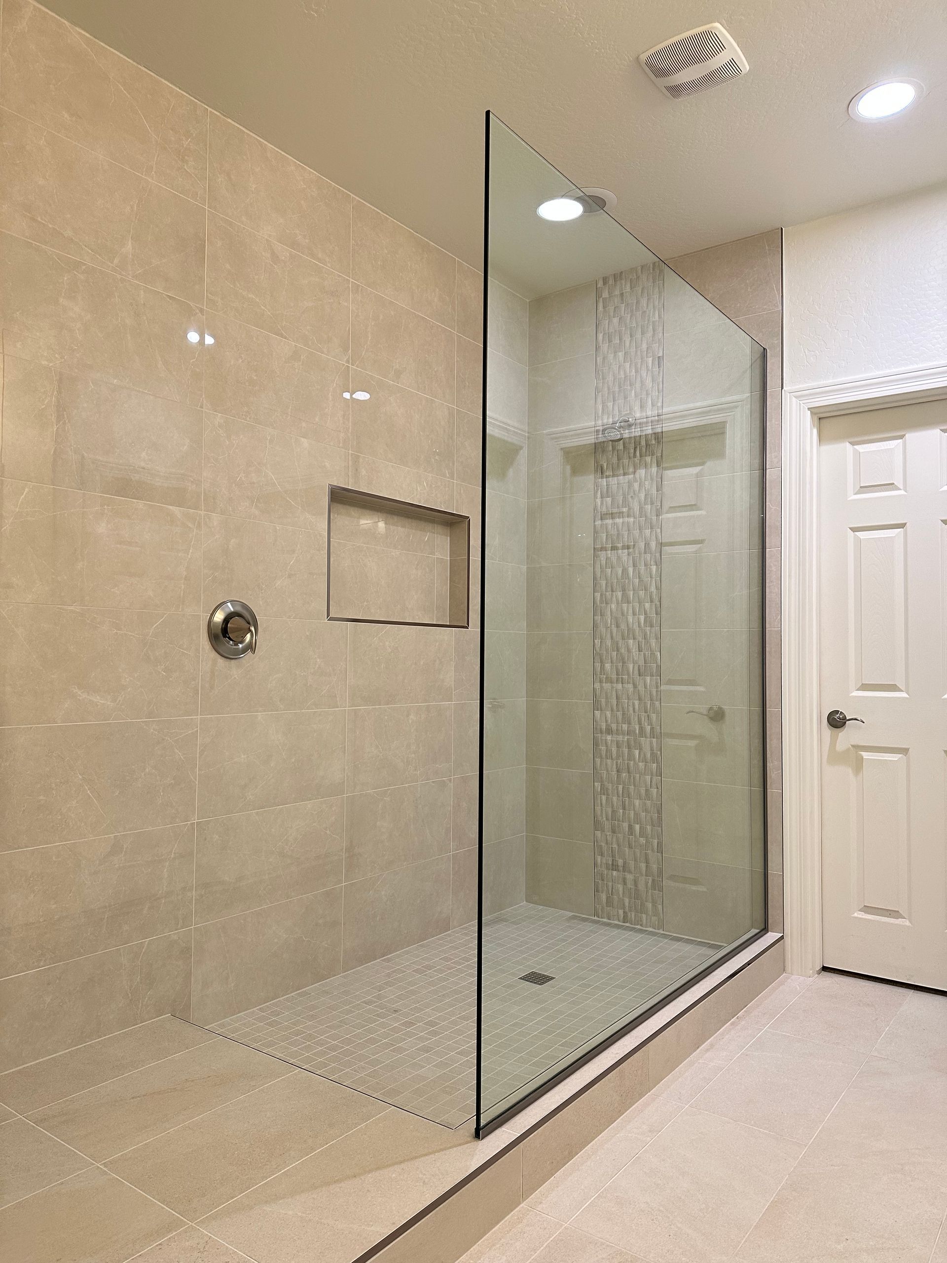A bathroom with a walk in shower with a glass door.