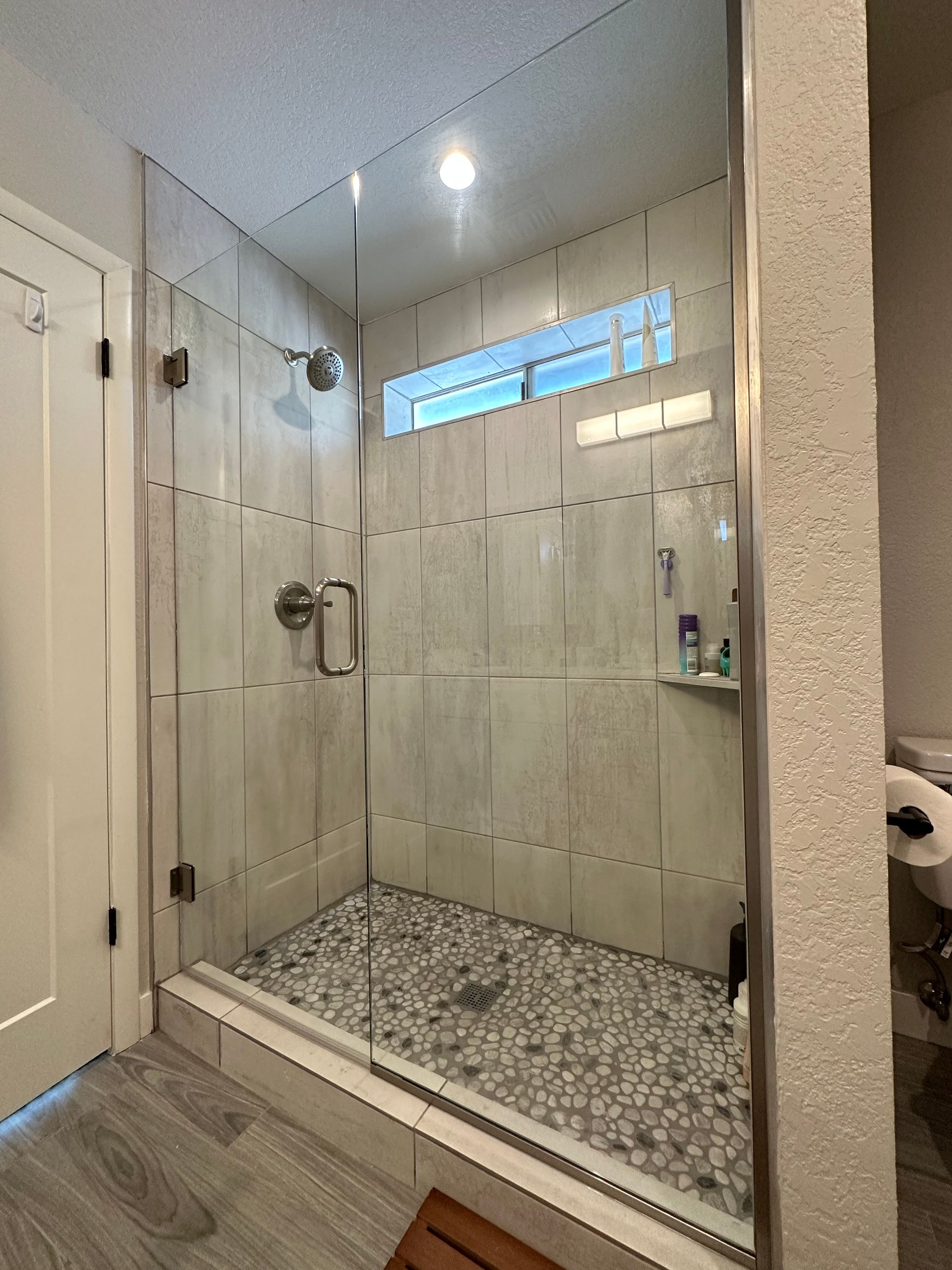 A bathroom with a walk in shower with a glass door.