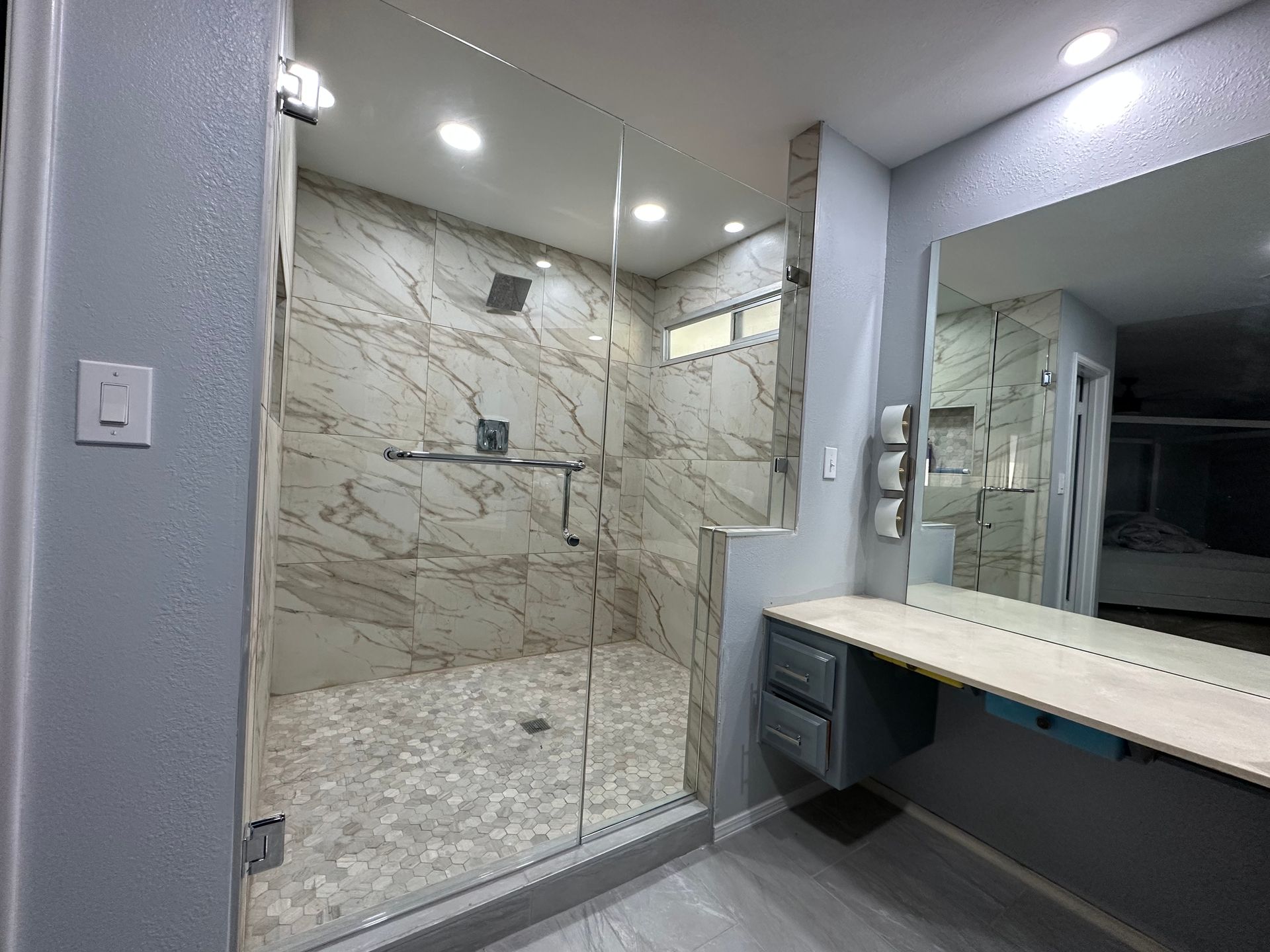 A bathroom with a walk in shower and a large mirror.