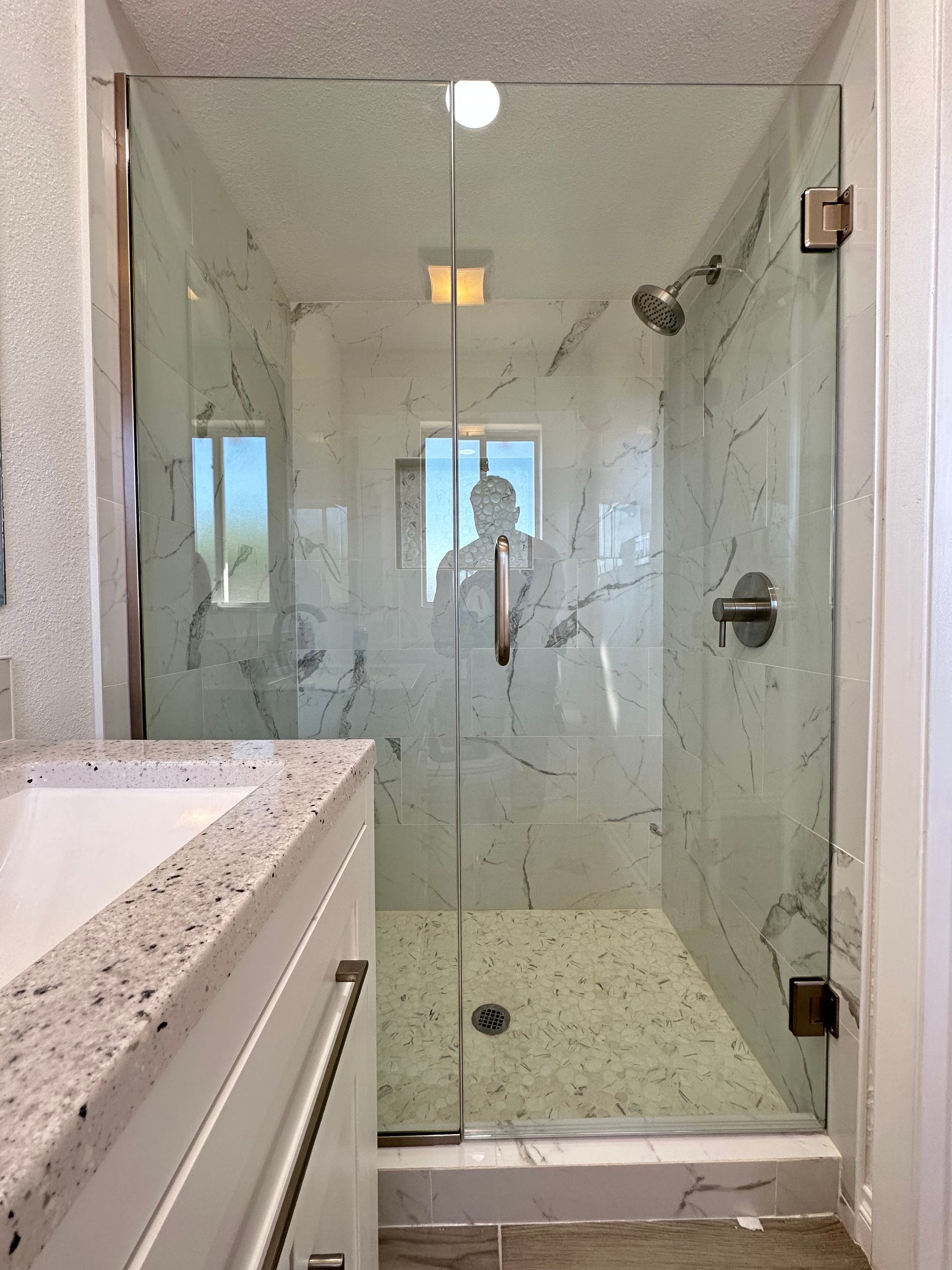 A bathroom with a walk in shower and a sink.