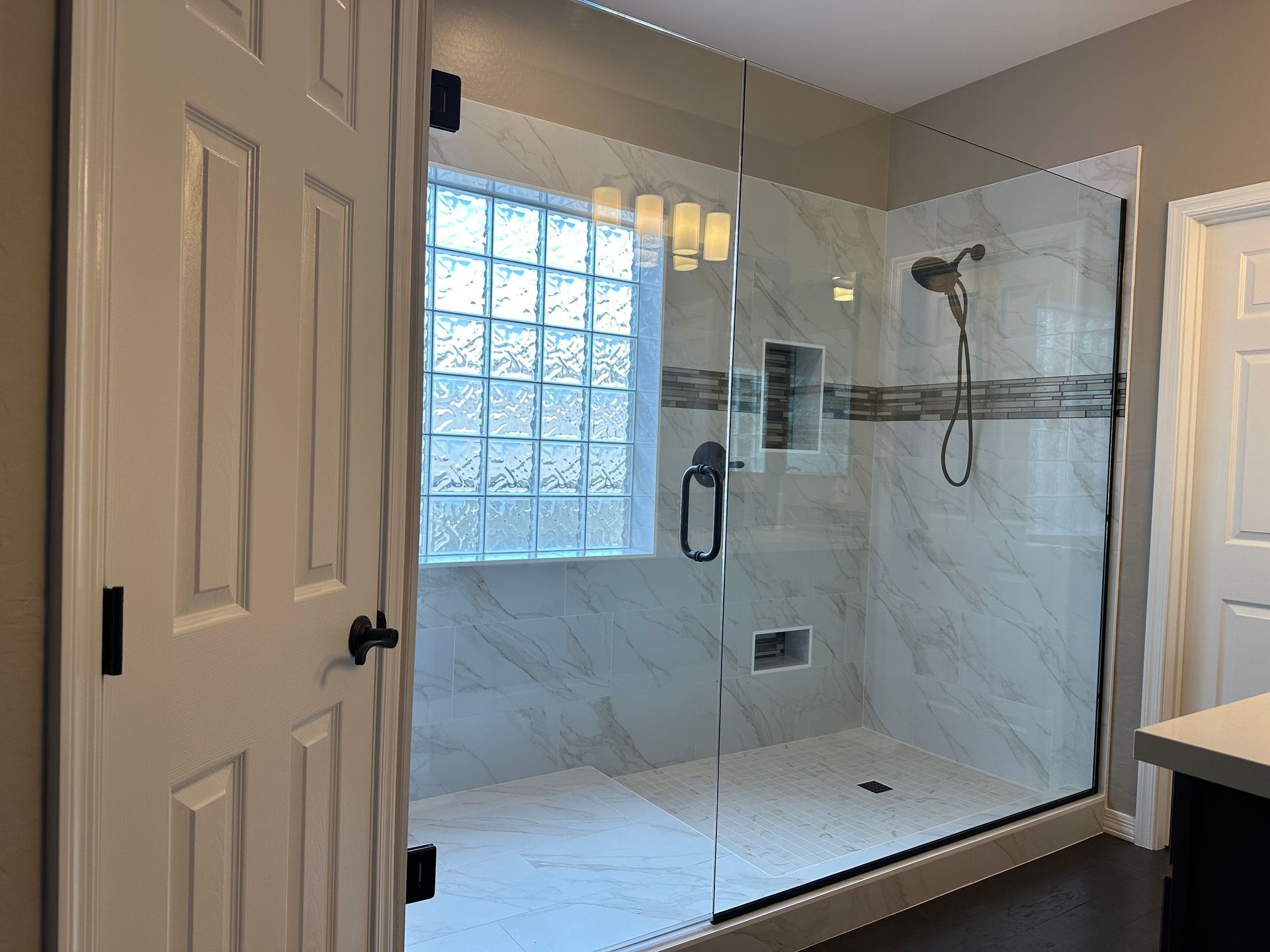 A bathroom with a walk in shower and a window.
