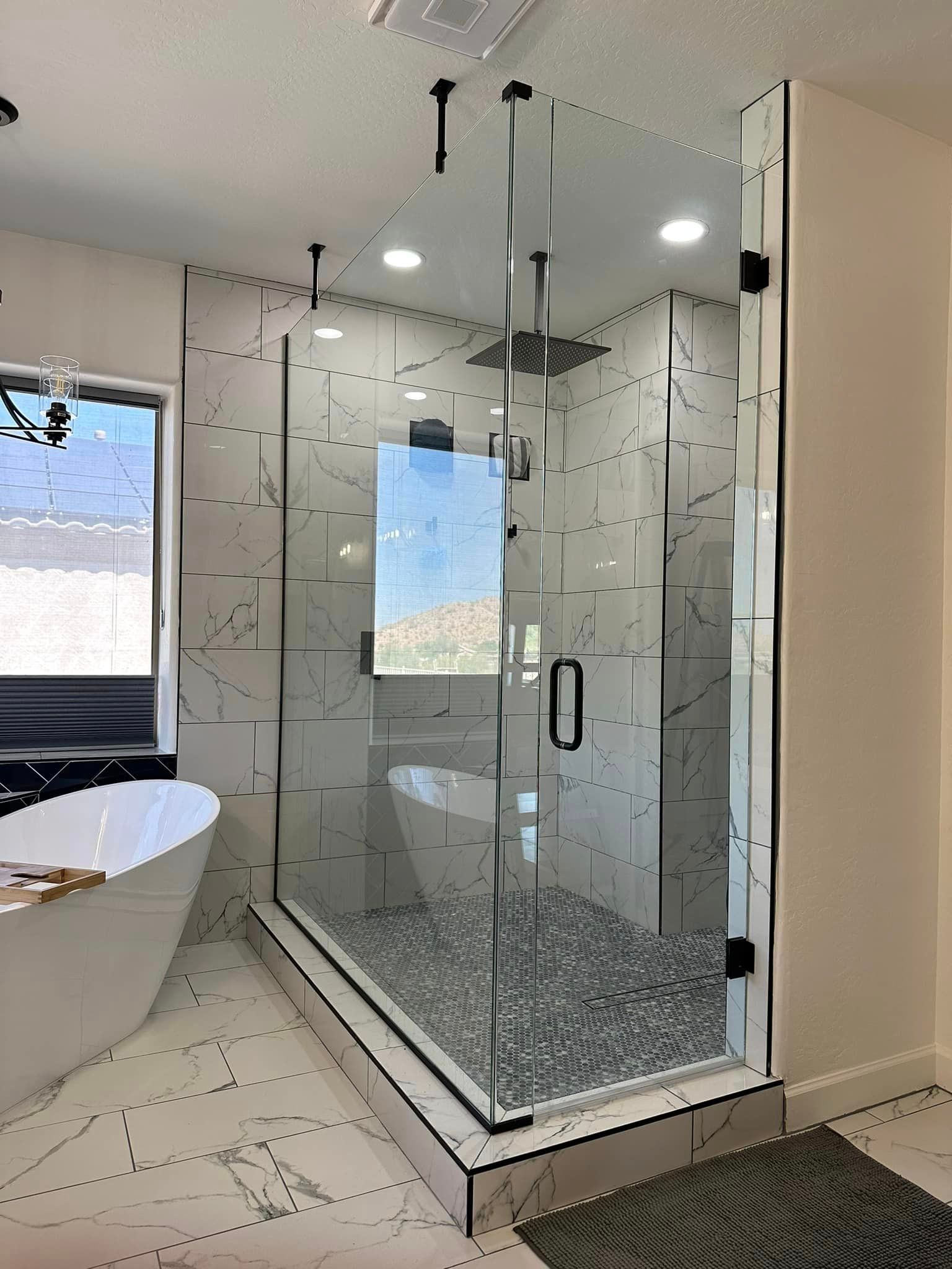 A bathroom with a walk in shower, tub, and window.
