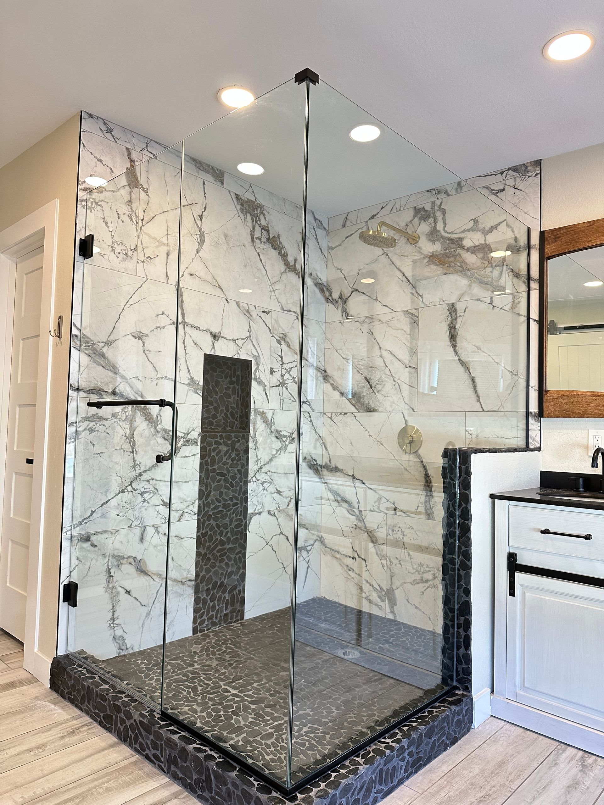 A bathroom with a walk in shower and marble walls.