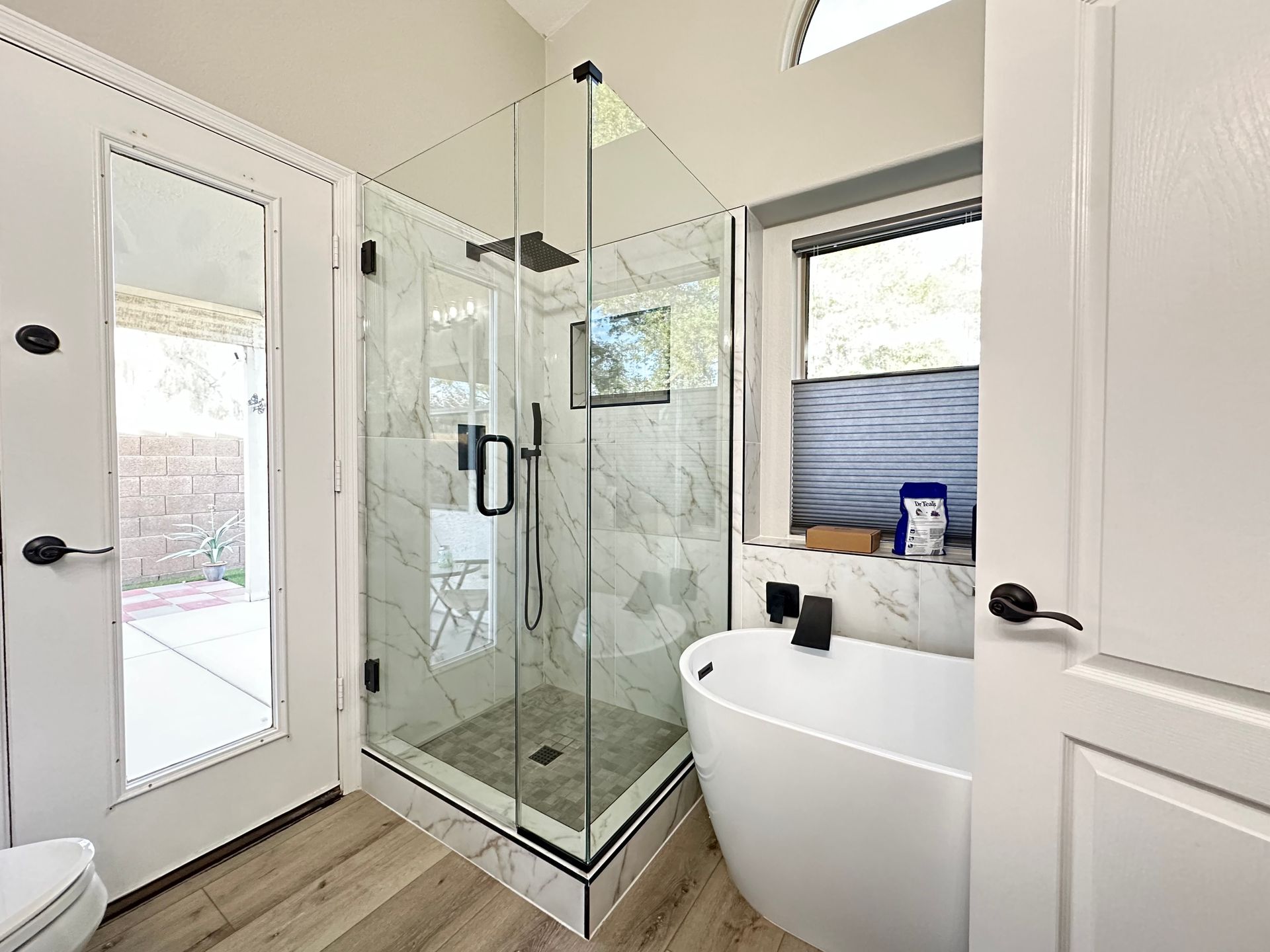 A bathroom with a tub , shower , toilet and mirror.