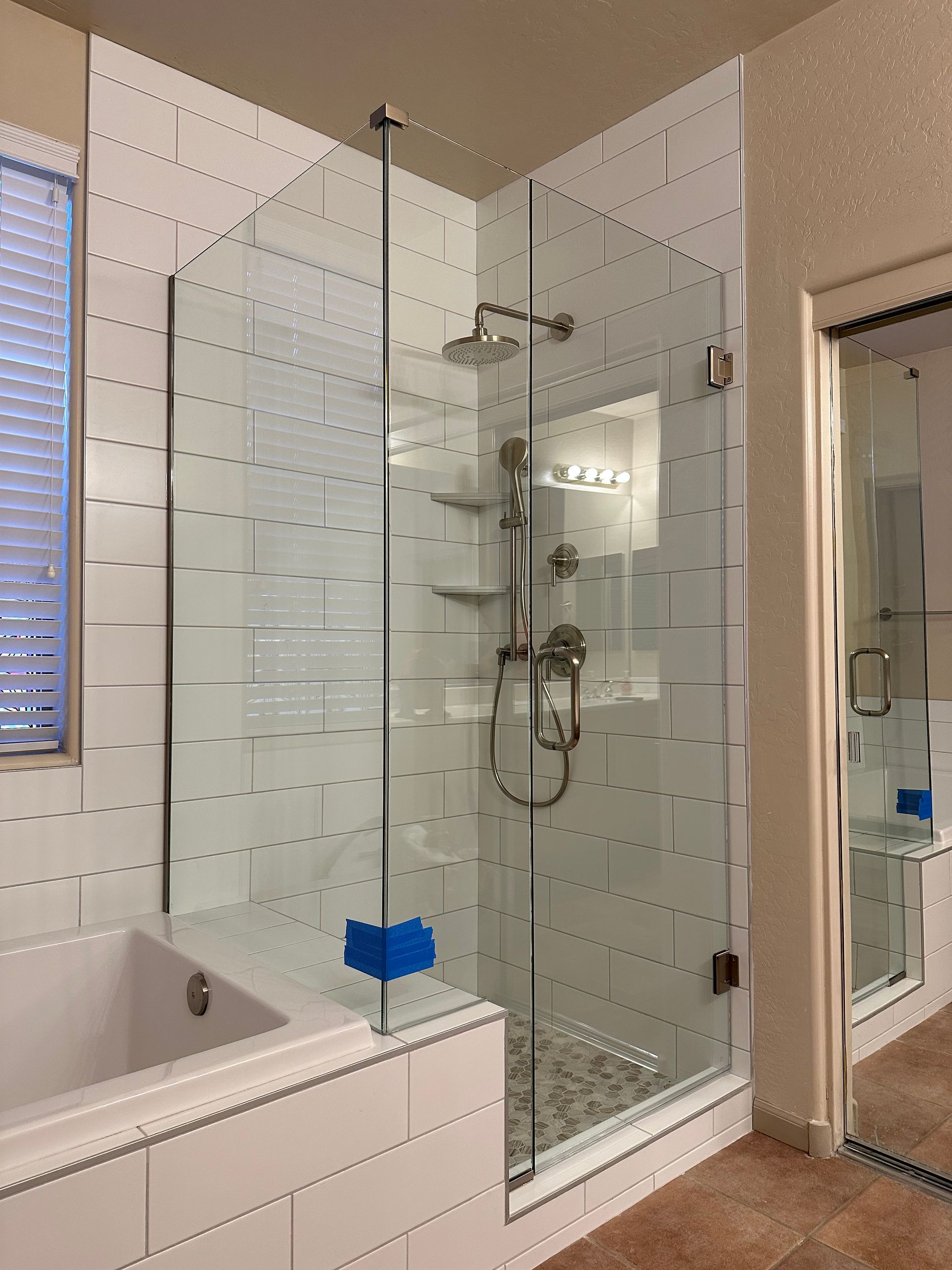 A bathroom with a tub and a shower with a glass door.