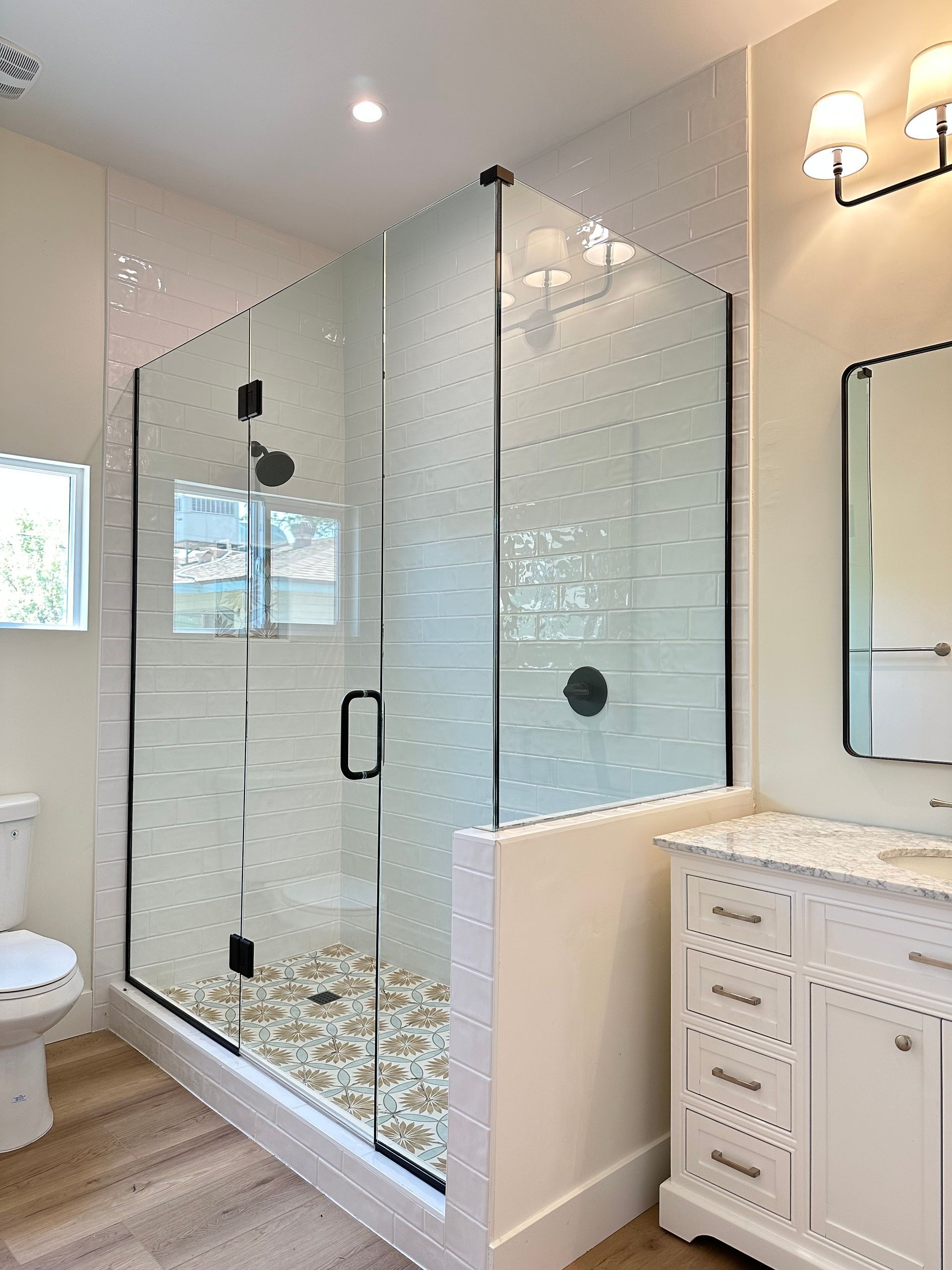 A bathroom with a walk in shower , sink and mirror.