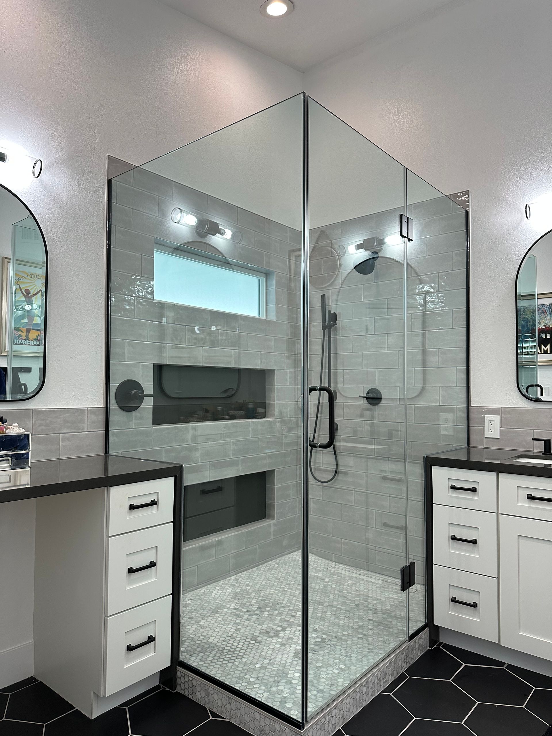 A bathroom with a walk in shower and two sinks.